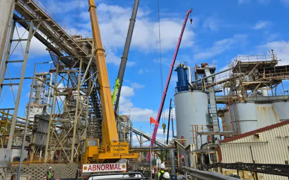Picture of three cranes moving heavy machinery on a job site