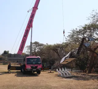 A picture of the Pink Lady crane lifting a stadium light at Lowveld High School
